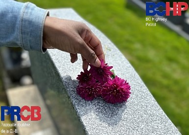 Une main dépose des fleurs sur une pierre tombale