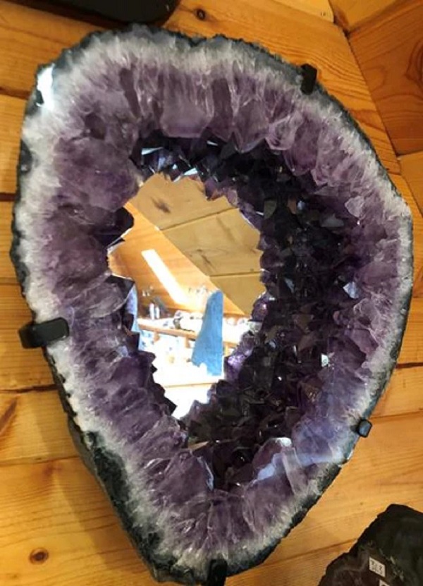 Purple amethyst crystal mirror mounted on wood wall