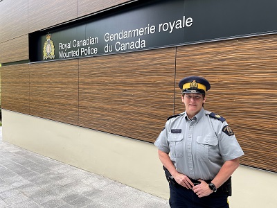 new detachment commander standing in front of rcmp sign