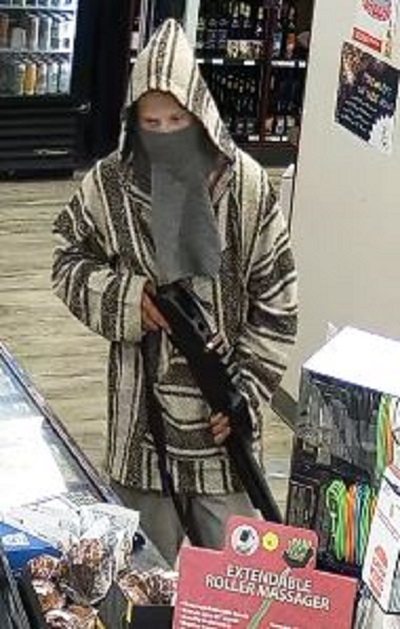 Description : Homme suspecté de vol, vêtu d’un poncho de style mexicain à rayures verticales brunes et beiges et d’une cagoule grise, tenant un fusil de chasse noir avec une seule cartouche rouge dans la partie supérieure de l’arme.