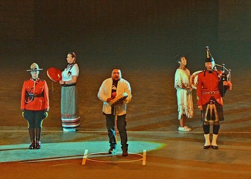 RCMP members in scarlet tunic standing with First Nations performers