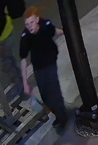 male youth suspect with short orange hair wearing a black hoodie with sleeves pushed up, and dark grey pants.