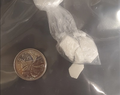 Prepackaged suspected crack cocaine with a quarter for comparison
